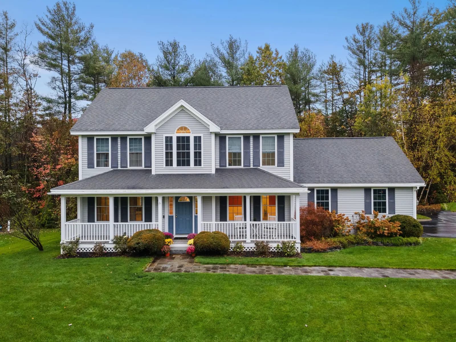 Green front lawn and shrub beds of a colonial home in fall