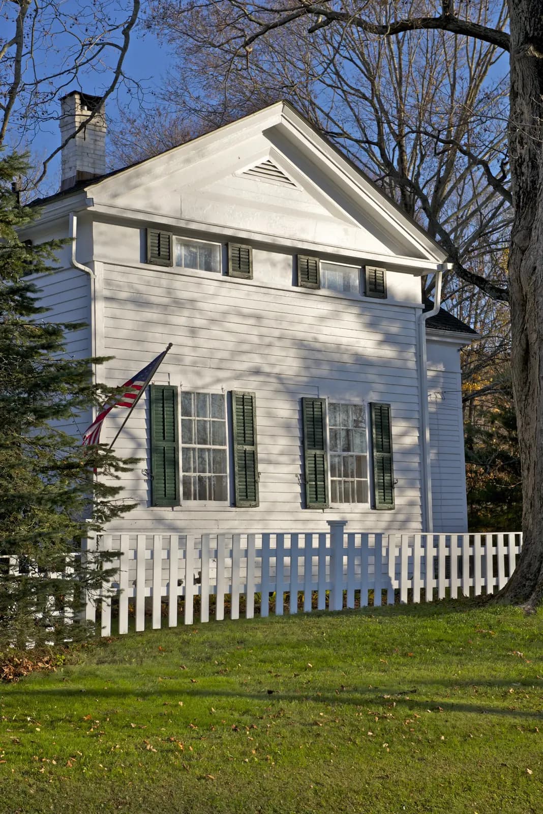 Neatly mowed lawn and picket fence in front of a New England home